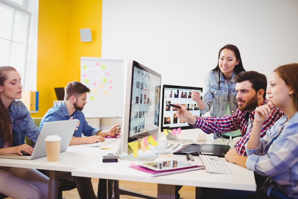 Businessman showing computer screen to coworkers in creative office Businessman showing computer screen to coworkers in creative office
